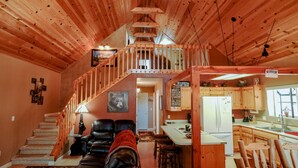 A cabin interior with a wooden staircase, a cozy living area with leather chairs, a kitchen with wooden cabinets, and a view of the outdoors. - SPECTACULAR COZY CABIN NESTLED IN THE PINES BIG FRONT DECK FENCED FOR DOGS (PINETOP)