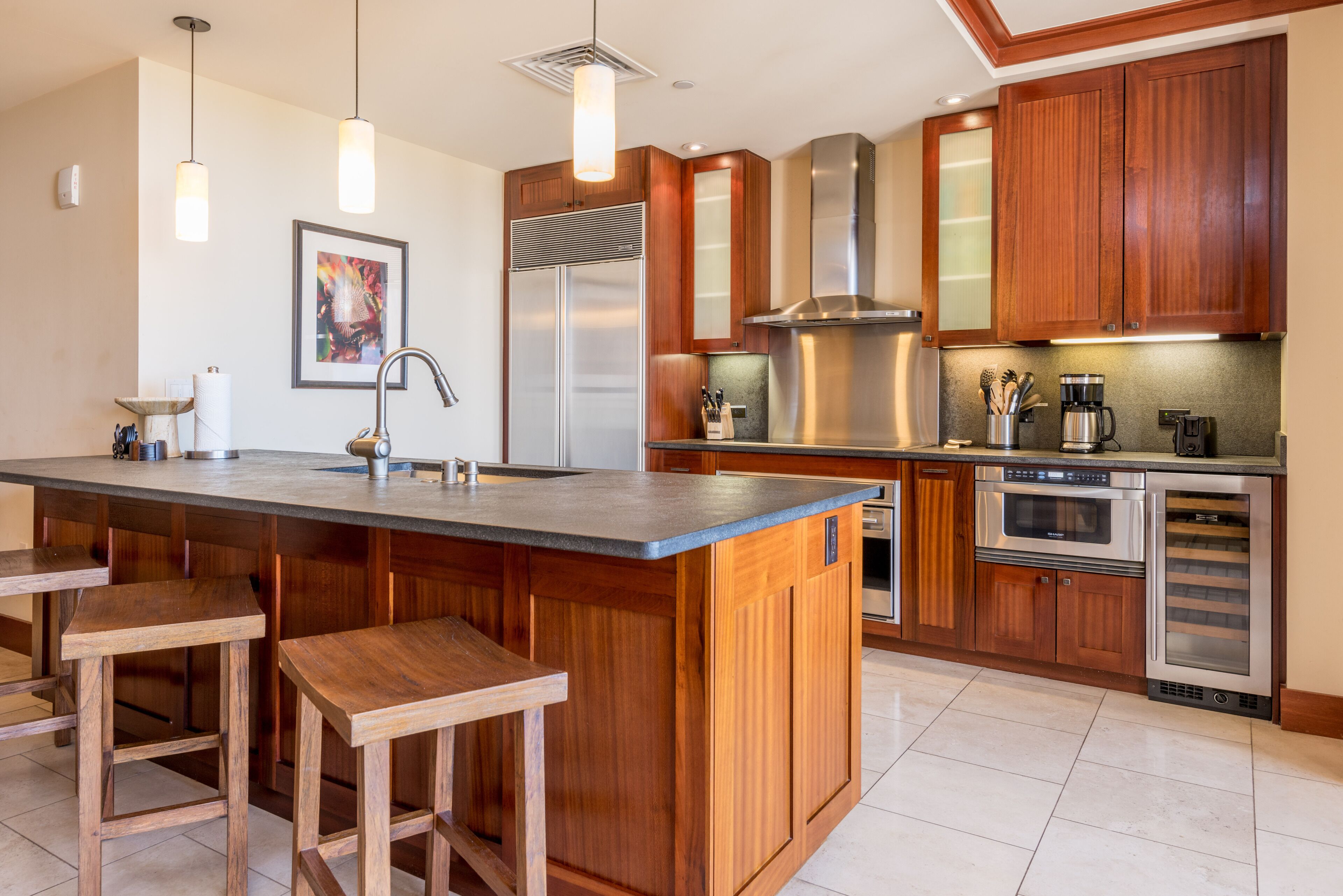 A modern kitchen with wooden cabinets, stainless steel appliances, and a central island with bar stools.