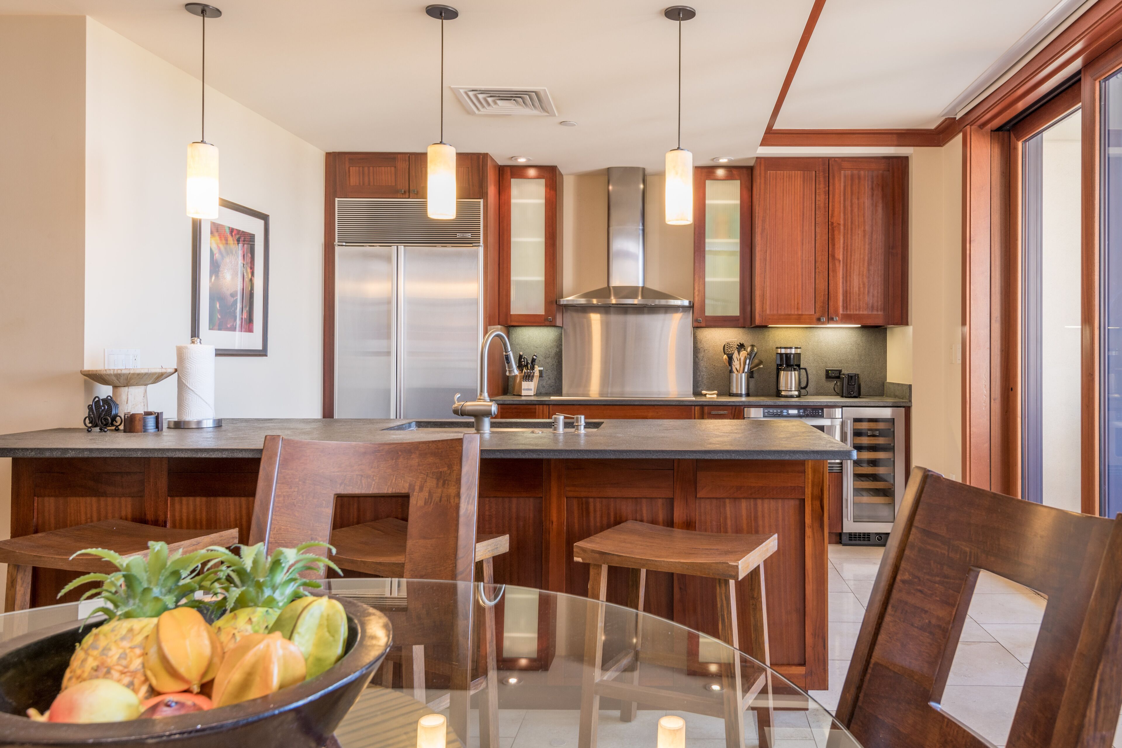 Una cocina moderna con armarios de madera, electrodomésticos de acero inoxidable y una mesa de comedor de vidrio con sillas.