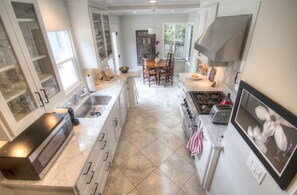 Enjoy cooking in this well-lit kitchen with a central island, oven, and stainless steel range hood.