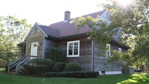 A two-story house with a gabled roof, a front porch, and a chimney.