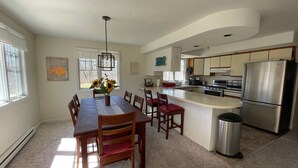 A modern kitchen with a central island, stainless steel appliances, and a dining area with a vase of sunflowers.