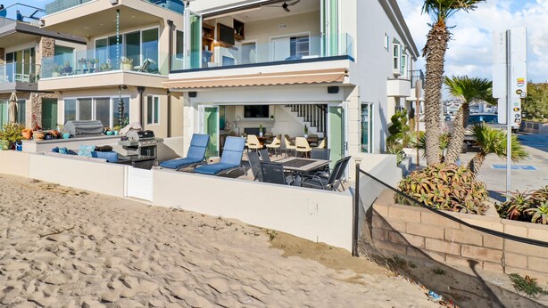 Ein modernes Strandhaus mit zwei Etagen, einem Balkon, Sitzgelegenheiten im Freien und Blick auf den Strand.