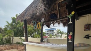 Een bar met rieten dak, een bord waarop 'Bay' staat, en een betegelde vloer.