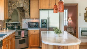 Une cuisine avec des meubles en bois, une arche en pierre, un four à micro-ondes, une bouilloire et des lanternes suspendues.