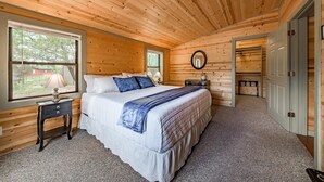 A wooden-paneled bedroom with a bed, bedside tables, a mirror, and a door leading to a closet.