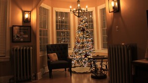 Una habitación cálidamente iluminada, con un árbol de Navidad, una araña y una silla.