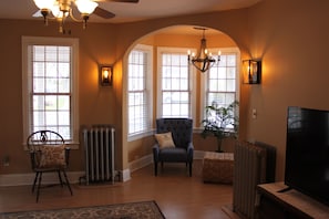 Relax in this inviting living room with a ceiling fan, comfortable armchair, and large window.