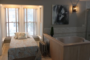 Cozy retreat with a large window, comfortable bed, and a beautiful painting.