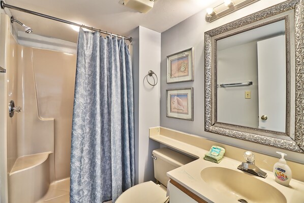 A bathroom with a shower, toilet, sink, and vanity.