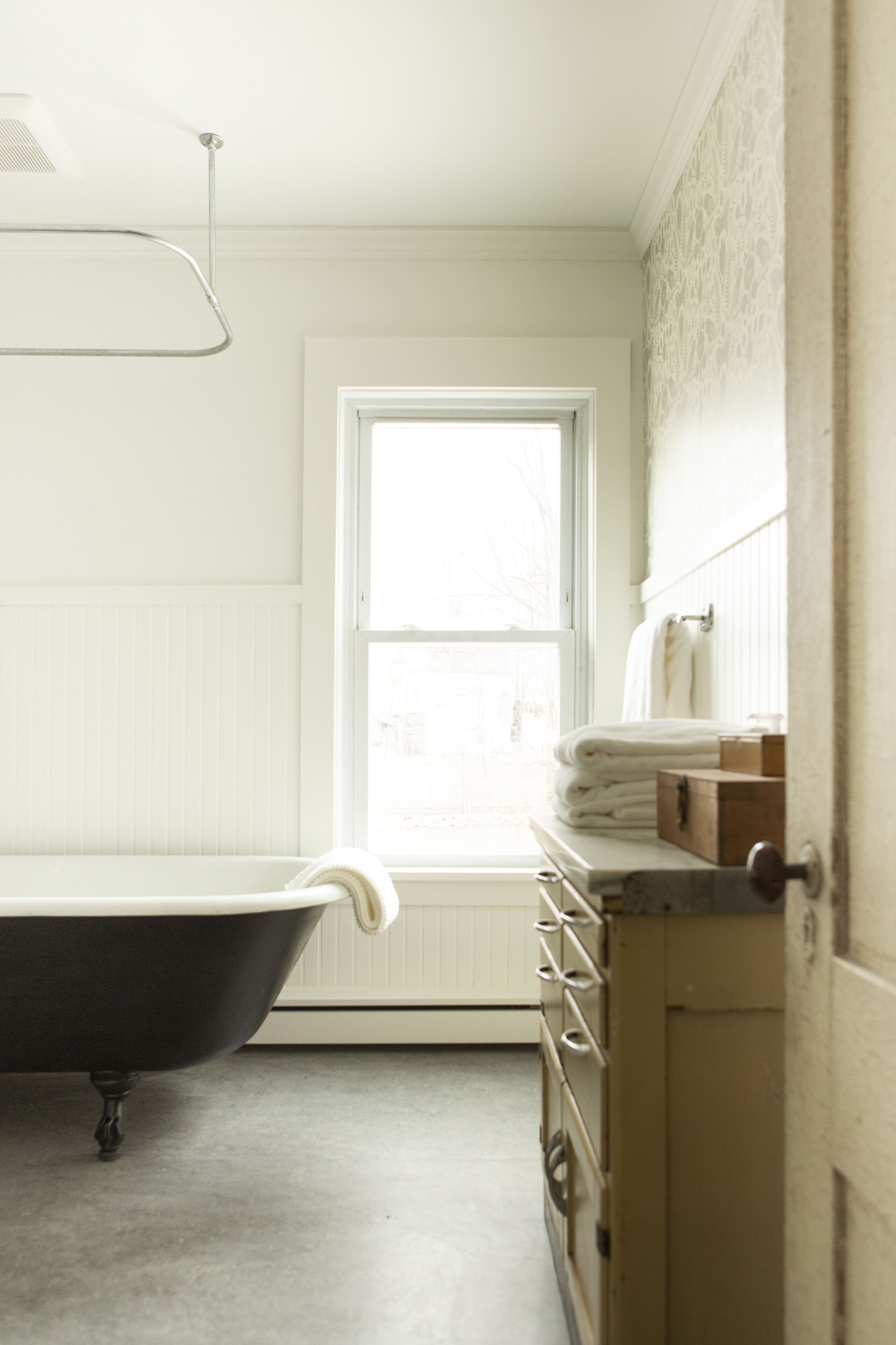 A bathroom with a bathtub, a window, and a towel rack.