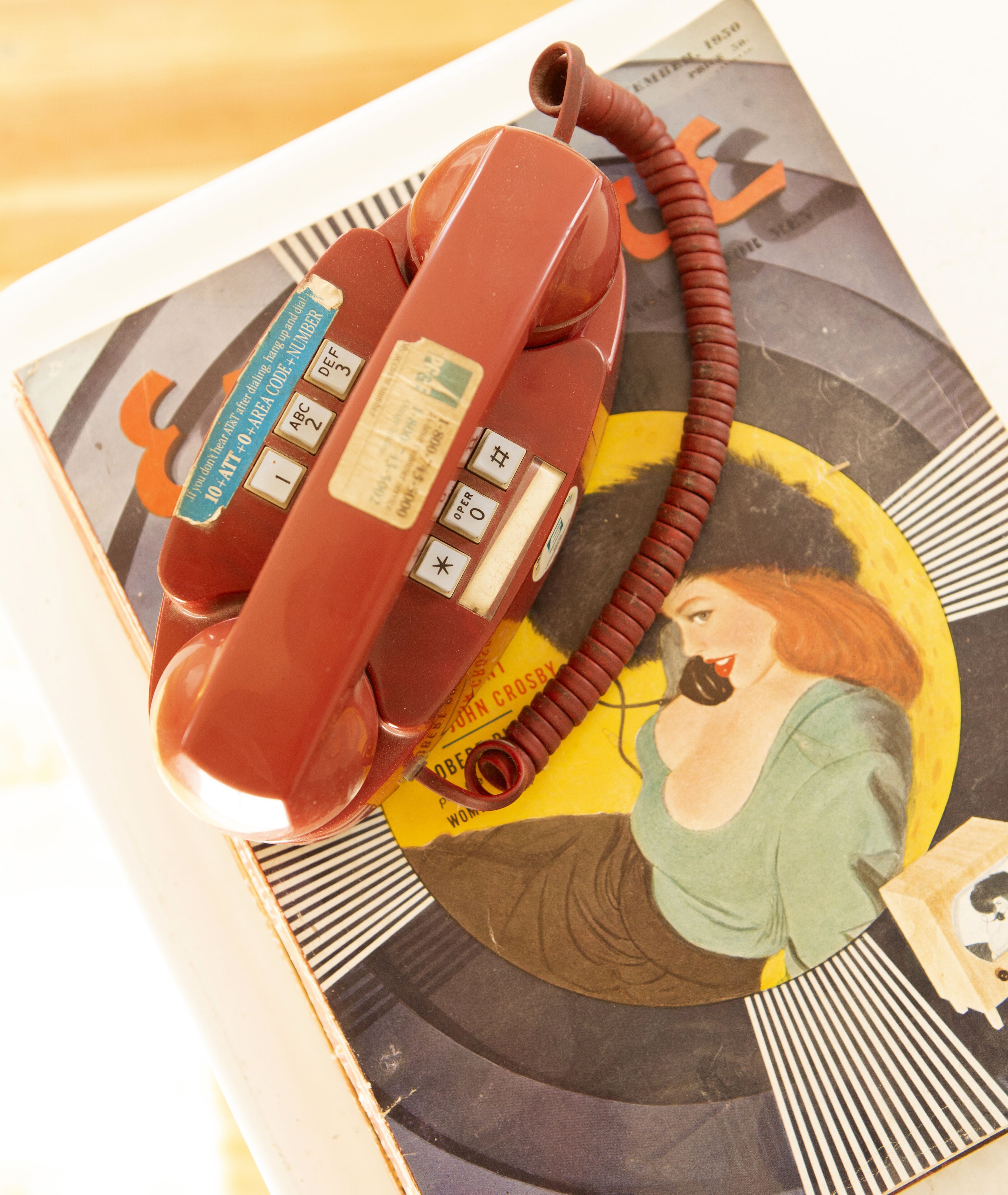 Un vieux téléphone à cadran rotatif posé sur un livre dont la couverture présente un motif circulaire.