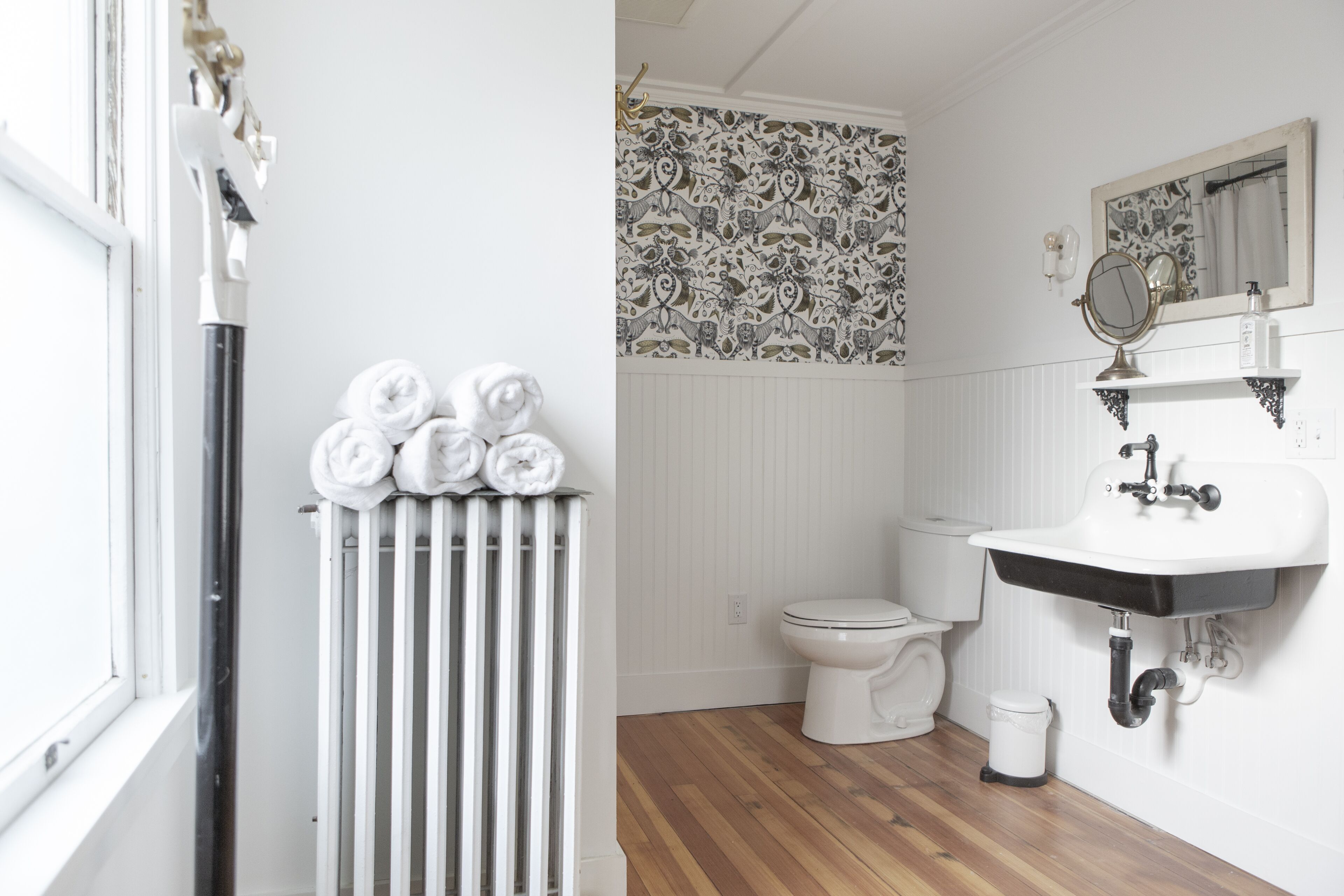 A bathroom with a radiator, a toilet, a sink, and a mirror.