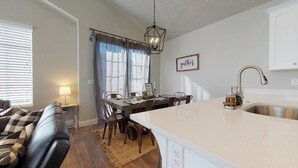 Une cuisine moderne avec un îlot central, un coin repas avec une table et des chaises, et un canapé dans l’espace salon.