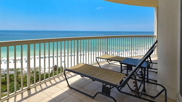 A balcony with a view of the beach and ocean.