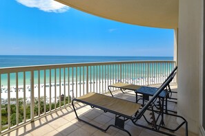 Een balkon met uitzicht op strand en zee.