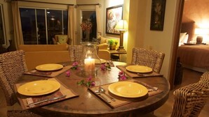 A dining area with a round table set for six, surrounded by wicker chairs.