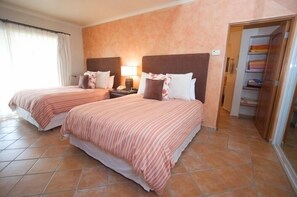 A hotel room with two beds, each with a headboard, a bedside table with a lamp, and a wardrobe in the corner. - COME to the best spot in Mexico!! Celebrate Labor Day In beautiful Los Cabos! (San Jose Del Cabo)
