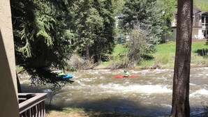 Ein Fluss mit einer Person im Kajak, umgeben von Bäumen und einem Gebäude im Hintergrund.