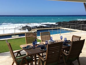 A table set for two with a view of the ocean and rocky coastline. - Location Location Location+Top 1% in guest service on Big Island Oceanfront Home (Kailua-Kona)