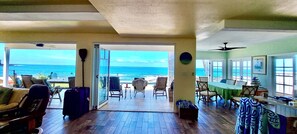 A room with a view of the ocean, a dining area, and a seating area with chairs and a table.