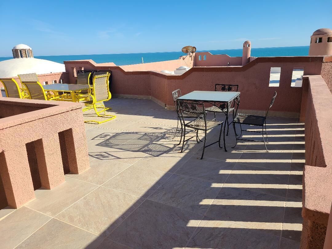 Une terrasse sur le toit avec une table et des chaises, une vue sur la mer et une structure en forme de dôme.