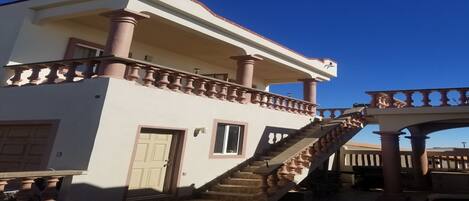 A two-story building with a balcony, a staircase, and a door.