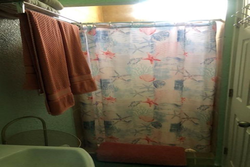 Een badkamer met een douchegordijn met een patroon van zeedieren, een handdoekhouder met handdoeken en een wastafel.