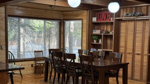 Un interior de madera con una mesa y sillas de comedor, ventanas amplias y un letrero con la palabra 'LOVE'.