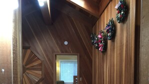 Un pasillo de madera con techo y piso de madera. Dos coronas decoran la pared.
