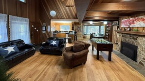 Un salón acogedor con mesa de fútbol, sofás de cuero y chimenea.