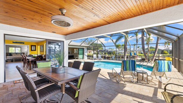 Un espace extérieur abrité comprenant une piscine, une table à manger et des chaises.