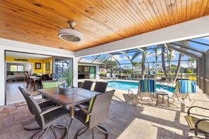 Un espacio al aire libre cubierto con piscina, mesa y sillas.