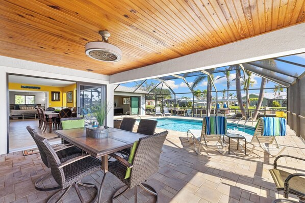 Une terrasse extérieure avec une piscine, un espace repas et une vue sur un quartier résidentiel.