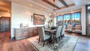 A spacious kitchen with wooden cabinets, a dining area with a large table and chairs, and a view through large windows. - Deep Forest Retreat | Big Sky Ski-In/Out Luxury for 10 (Big Sky)