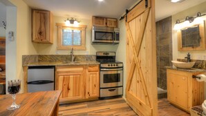 A kitchen with wooden cabinets, a stainless steel oven, a microwave, and a sink with a marble countertop. - Creekside Tiny Cabin w/ Hot Tub, Firepit, Pet Friendly, Near NOC, Tsali & Dragon (Almond)