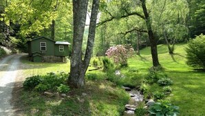A rustic cabin with a small stream running through a lush garden. - Creekside Tiny Cabin w/ Hot Tub, Firepit, Pet Friendly, Near NOC, Tsali & Dragon (Almond)
