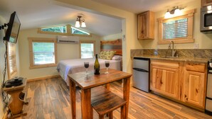 A compact kitchen with wooden cabinets, a granite countertop, and a built-in oven. - Creekside Tiny Cabin w/ Hot Tub, Firepit, Pet Friendly, Near NOC, Tsali & Dragon (Almond)