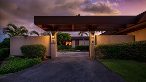 A driveway leading to a building with a covered entrance, palm trees, and well-maintained hedges. - Mauna Kea Villa, Walking Distance to the Beach and Hotel - Beyond Perfection! (Kamuela)