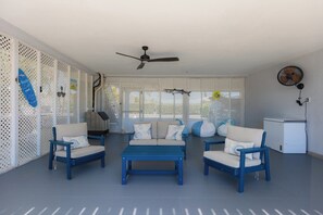 Ein Zimmer mit Deckenventilator, Möbel in Weiß und Blau sowie ein weißer Kühlschrank.