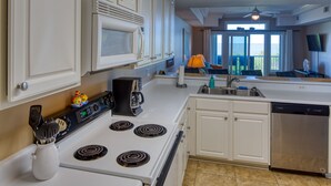 Une cuisine avec des meubles blancs, une cuisinière, un four à micro-ondes et un lave-vaisselle.