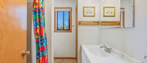 A bathroom with a white sink, a mirror, and a shower curtain.