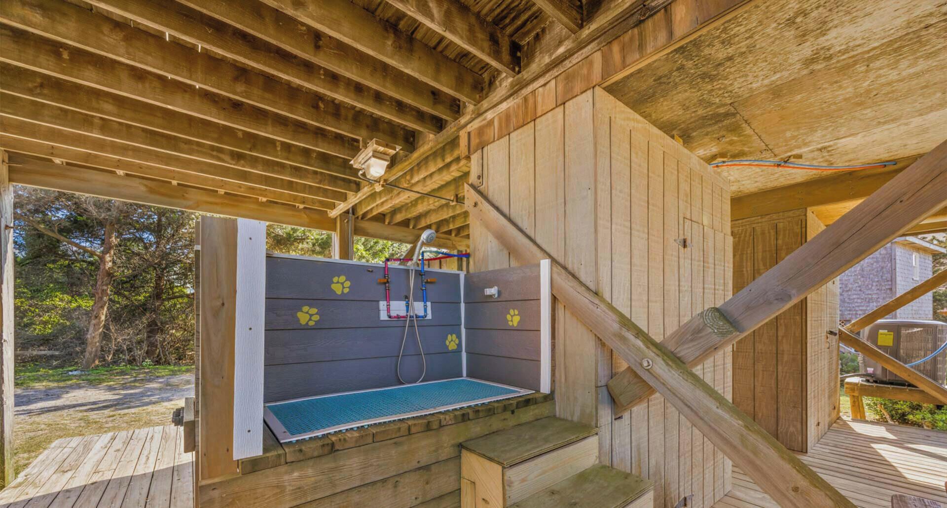 A wooden structure with a built-in shower area, including a bench and a hose.
