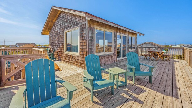 A wooden cabin with a deck, outdoor seating, and a view of the ocean. - Oceanview Dog Friendly w/ Hot Tub, Games, Community Pool and Tennis/Pickleball (Avon)