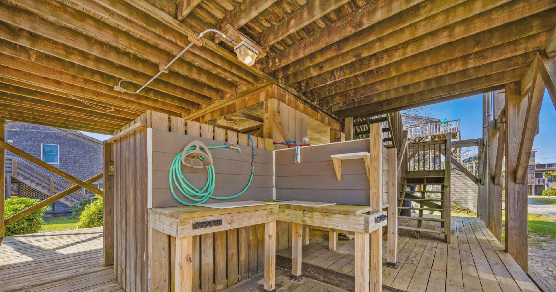A wooden deck with a bench and a hose.