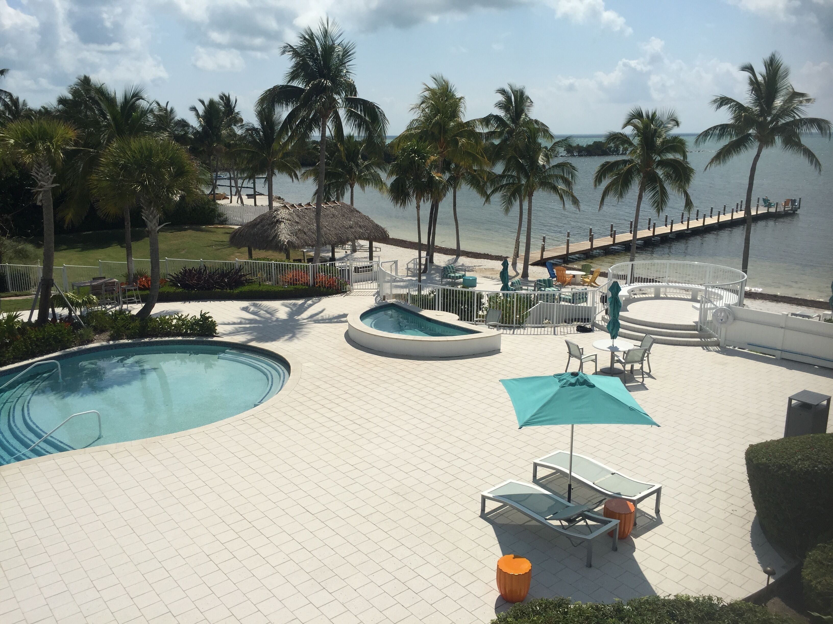 A pool area with lounge chairs, a small pool, and a view of the ocean.