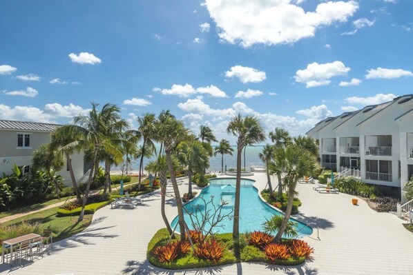 Un complexe hôtelier doté d’une piscine, de palmiers et offrant une vue sur la plage.