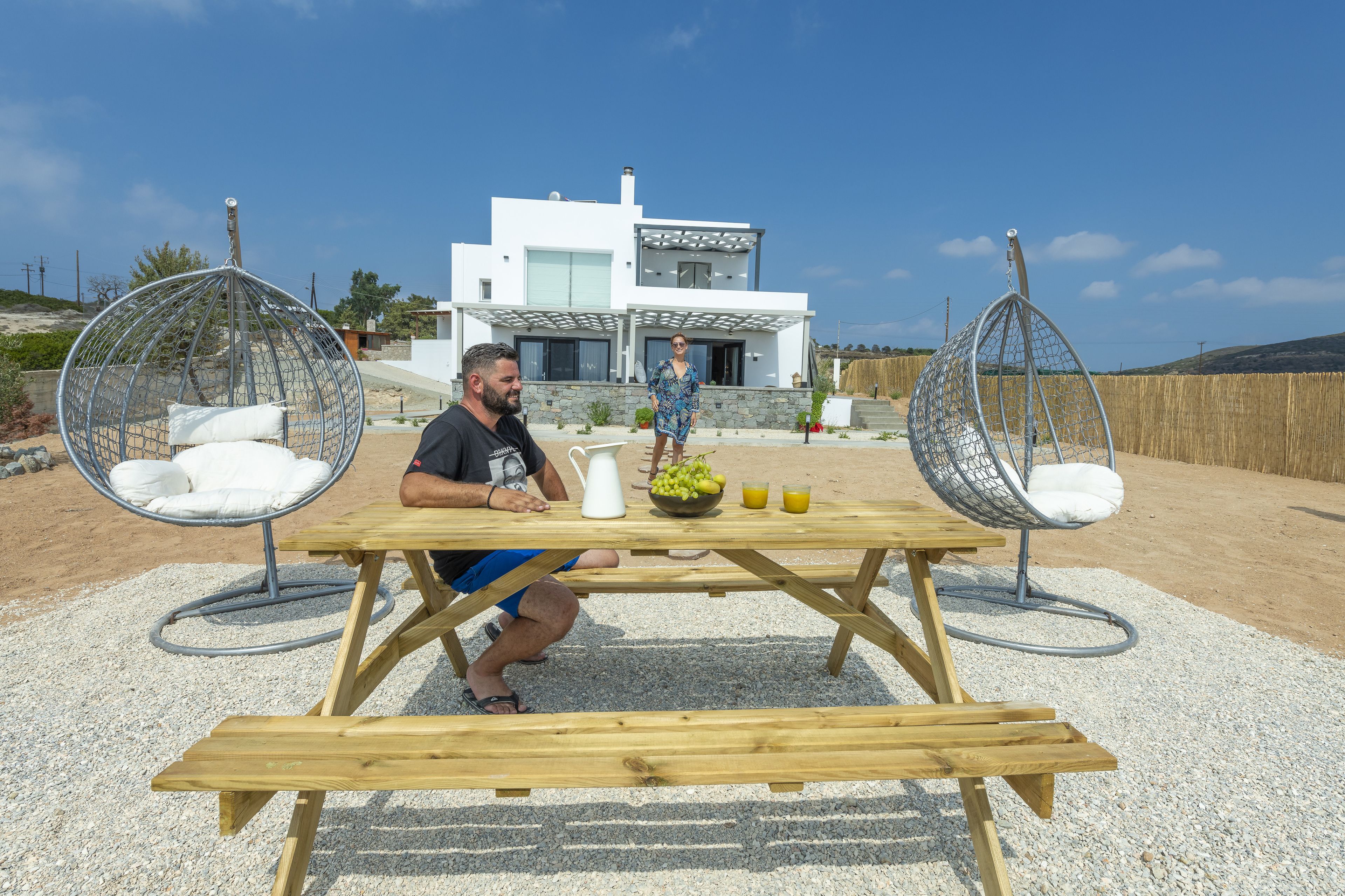 Una casa moderna con una mesa de patio y dos sillas colgantes.