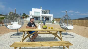 Una casa moderna con una mesa de patio y dos sillas colgantes.