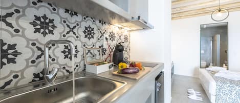 A modern kitchen with a stainless steel sink, a patterned backsplash, and a wooden cutting board with vegetables.